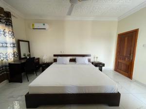 een slaapkamer met een groot wit bed en een bureau bij JD Hotel And Bar. in Accra