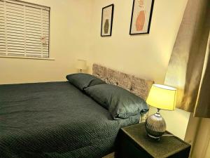 a bedroom with a bed and a table with a lamp at Modern & Cosy 1 bedroom flat in Bridgend