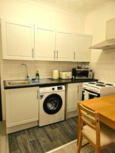 een keuken met een wasmachine en een wastafel bij Modern & Cosy 1 bedroom flat in Bridgend