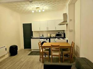 a kitchen with a table and chairs in a room at Modern & Cosy 1 bedroom flat in Bridgend