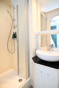 La salle de bains blanche est pourvue d'un lavabo et d'une douche. dans l'établissement Self check in City HoStel Nordstern, à Essen