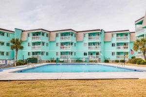 a building with a swimming pool in front of a building at Chic Condo with Ocean Views and Pool - Walk to Beach! in Atlantic Beach