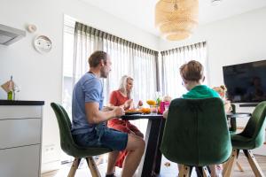 um grupo de pessoas sentadas numa mesa numa cozinha em Vakantiehuis met omheinde tuin em Dokkum