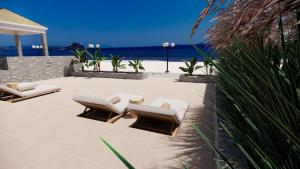 a patio with two lounge chairs and the ocean at Nalu Luxury Suites in Kefalos