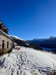 L'Impradine, grand gîte vue et nature splendides في Le Falgoux: طريق مغطى بالثلج بجوار مبنى على جبل