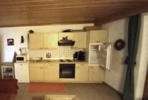 cocina con armarios blancos y nevera en FeWo LEO im AKTIV Landhaus en Missen-Wilhams
