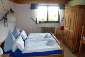 1 dormitorio con cama con sábanas azules y ventana en FeWo LEO im AKTIV Landhaus, en Missen-Wilhams