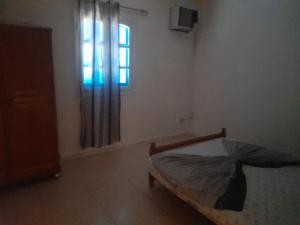 - une chambre avec un lit dans une pièce dotée d'une fenêtre dans l'établissement Appartement R2 dans résidence, à Houmt Souk