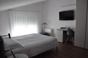 a white bedroom with a bed and a desk at Kalé in Pordenone