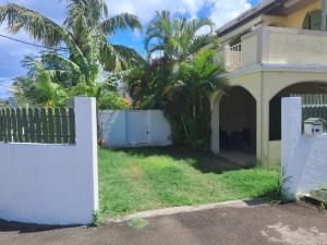 a white fence in front of a house with palm trees at IZS MAURICE in Trou aux Biches