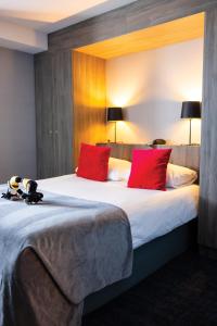 ein Hotelzimmer mit einem großen Bett mit roten Kissen in der Unterkunft Van der Valk Hotel Liège Congres in Lüttich
