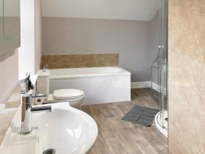 La salle de bains est pourvue de toilettes blanches et d'un lavabo. dans l'établissement Halleaths Home Farm, à Lochmaben