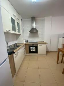 uma cozinha com armários brancos e um forno com placa de fogão em Los Cristianos, Tenerife em El Guincho