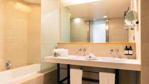 a bathroom with two sinks and a mirror and a tub at NH Collection Mexico City Airport T2 in Mexico City