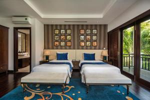 a bedroom with three beds with blue pillows at Abogo Champa Villa Beach Da Nang in Da Nang
