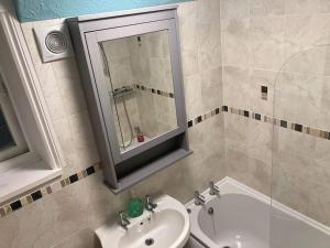 a bathroom with a sink and a mirror and a tub at Lawn View Apartment in Dawlish