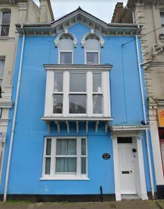 a blue house with white windows on a street at Lawn View Apartment in Dawlish