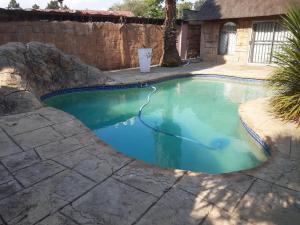 a swimming pool in a backyard with a stone wall at FK Guest Inn in Alberton