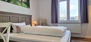 a bedroom with a white bed and a window at Gästehaus Teerlings Hafen in Borkum