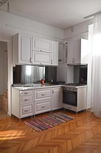 cocina blanca con armarios blancos y suelo de madera en Vintage Dream Apartment, en Oradea