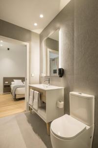 a bathroom with a toilet and a sink and a bed at Mon Suites Jardín de Ayora in Valencia