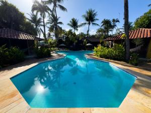 a blue swimming pool with palm trees in the background at Pousada Berro do Jeguy in Pipa