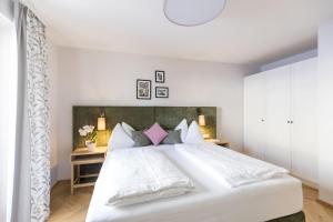 a bedroom with a large white bed with pink pillows at Familienhotel Felsenhof in Flachau
