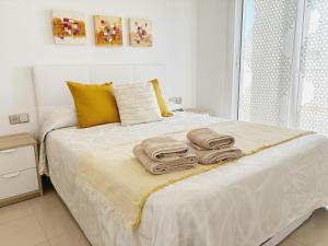 een slaapkamer met een bed met handdoeken erop bij Ático en pimera línea de playa in Roquetas de Mar