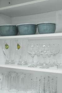 a shelf filled with wine glasses and blue bowls at Magico Home City Heart Luxury Appartment in Alexandroupoli