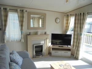 a living room with a television and a fireplace at Kingfisher Windermere 6 Berth, Enclosed veranda, Close to site shop in Ingoldmells
