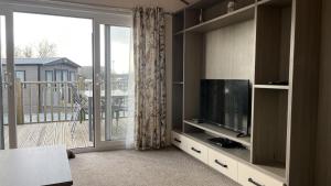 a living room with a television and a balcony at 2-Bed Lodge Near Garstang and Poulton-Le-Fylde in Preston