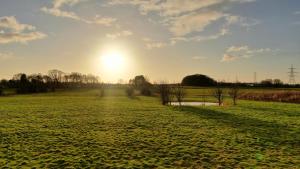 un campo con il tramonto del sole sullo sfondo di 2-Bed Lodge Near Garstang and Poulton-Le-Fylde a Preston