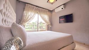 Un dormitorio con una cama grande y una ventana en Corail Apart Golfique -Prestigia en Marrakech