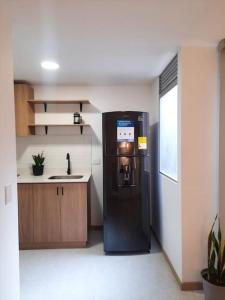 a black refrigerator in a kitchen with a sink at Cozy Apartment in Historic Prado with adjustable desk and 4K Monitor in Medellín