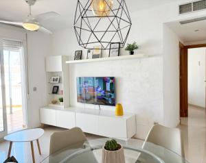 een woonkamer met een tv en een tafel bij Ático en pimera línea de playa in Roquetas de Mar