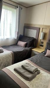 1 Schlafzimmer mit 2 Betten und einem Fenster in der Unterkunft Immaculate 3-Bed Lodge in Out Rawcliffe in Great Eccleston