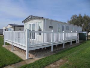 a white mobile home with a white fence at Kingfisher Windermere 6 Berth, Enclosed veranda, Close to site shop in Ingoldmells