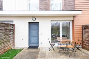 a porch with a table and chairs and a blue door at Disney à 10 min: Maison paisible 8P, Wifi, Parking in Chessy