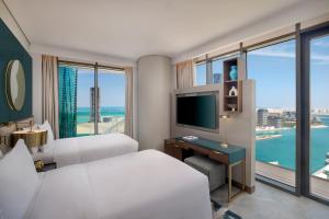 a hotel room with two beds and a television at Conrad Bahrain Financial Harbour in Manama