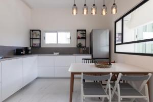 テルアビブにあるCozy 2BR Heart in Tel Avivの白いキャビネット、テーブルと椅子付きのキッチンが備わります。