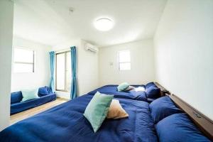 a bedroom with a large bed with blue sheets at AKIZUYA STAY Miyakojima in Miyako Island