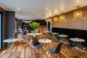 ヨハネスブルグにあるBedfordview Hotel & Apartmentsの白いテーブルと椅子、照明が備わるレストラン