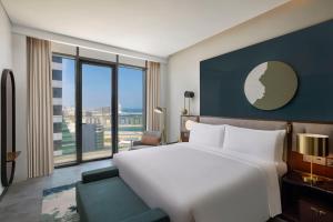 a bedroom with a large bed and a large window at Conrad Bahrain Financial Harbour in Manama