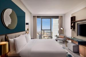 um quarto de hotel com uma cama grande e uma janela grande em Conrad Bahrain Financial Harbour em Manama