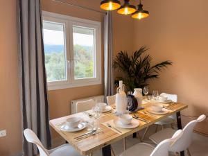 a dining room table with white chairs and a window at Terpsichore's House in Sami