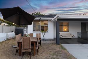 a table with chairs and an umbrella in a backyard at Cozy 5 bed House Nr Airport/DFO/Casino in Perth