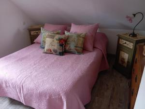 Un dormitorio con una cama rosa con sábanas y almohadas rosas. en La petite maison dans la prairie, en Notre-Dame-du-Touchet