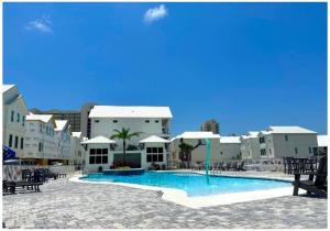 una gran piscina en un complejo con mesas y sillas en Ta-Kee-La Sunset at The Osprey, en Orange Beach