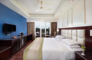 a bedroom with a large bed and a television at The Acacia Hotel & Spa in Candolim