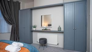 a bedroom with a bed with blue cabinets and a mirror at 1 BDR apartment at QUEENS UNI by Belfast City Breaks in Belfast